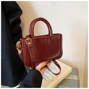 Dettaglio di borsa vintage in pelle cerata rosso scuro con finiture in metallo oro