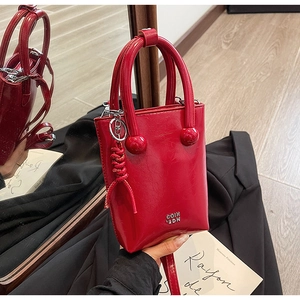 Detail of red glossy oil wax leather handbag with bead handle and metal logo