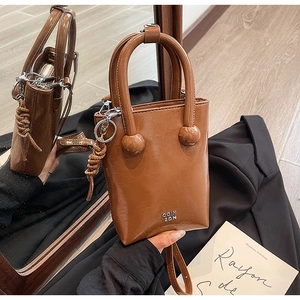 Detail of a brown oil-waxed leather handbag featuring a silver logo and textured finish