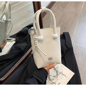 Detail of minimalist cream leather crossbody bag with silver metallic ball hardware and logo
