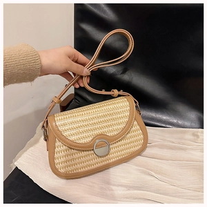 Detail of woven straw bag with tan leather trim and silver metal magnetic closure
