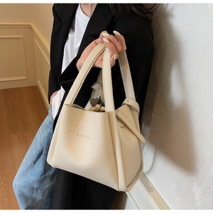 Detail shot of beige lychee grain leather bucket bag with debossed HAMIEOS logo and fine stitching