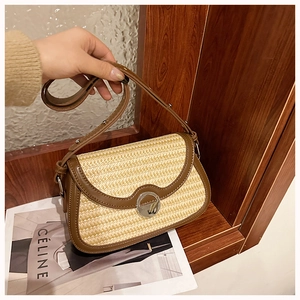 Detailed close-up of woven straw saddle bag with dark brown leather trim and silver lock