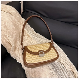 Detail of woven straw shoulder bag with dark brown leather trim and silver metal clasp