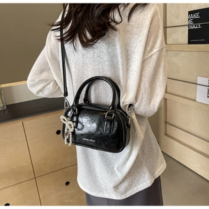 Detail of black wax leather Boston bag with pearl bow charm and LANGE & SHIJIA logo