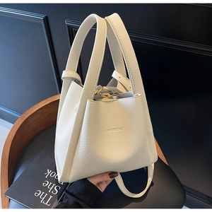 Detailed macro shot of lychee grain leather and embossed logo on beige bucket bag