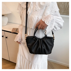 Détail du sac noir en cuir grainé avec un élégant design plissé et des finitions dorées