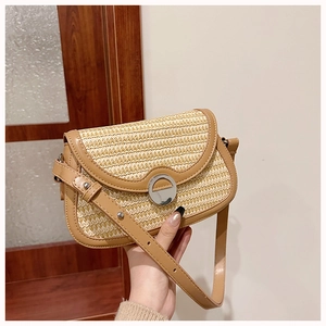 Close-up of the woven straw shoulder bag with brown leather trim and silver metal lock