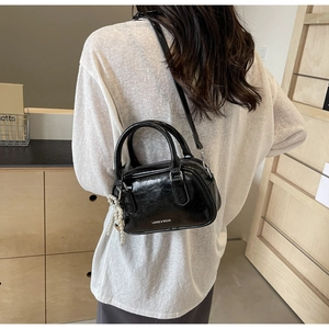 Detail of oil wax leather Boston bag featuring elegant pearl pendant and branding