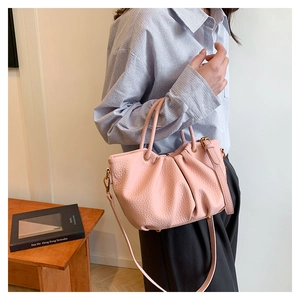 Détail du sac bandoulière rose plissé avec texture litchi et accessoires dorés élégants