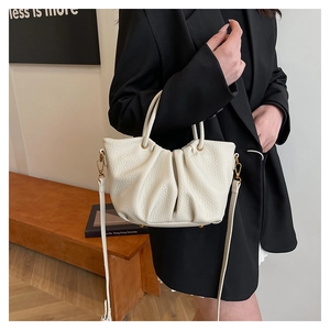 Détails de la texture cuir litchi et du design plissé sur le sac seau crème chic