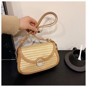 Close-up of beige straw woven bag with brown leather trim and silver metal ring buckle
