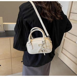 Close-up of cream white Boston mini bag featuring pearl bow and heart pendant detail
