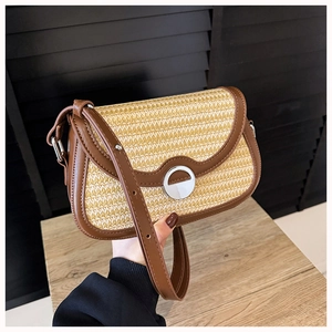 Detail of woven straw shoulder bag with dark brown leather trim and silver metal lock