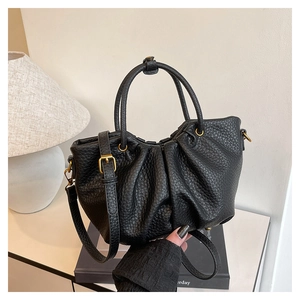 Détail du sac en cuir noir avec texture litchi et finitions métalliques dorées