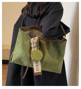 Detail of green quilted tote bag with brown leather trim and CLEAR lettered strap