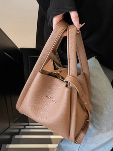 Brown lychee leather bucket bag with top handle and gold hardware shown in lifestyle scene