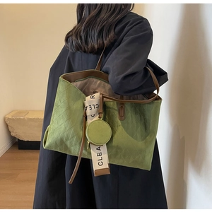 Detail view of green suede tote bag with diamond quilted pattern and a small coin purse