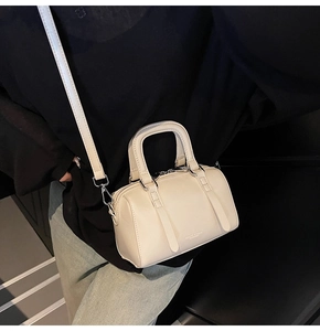 Détail du sac Boston crème avec doubles poignées et bandoulière réglable en similicuir