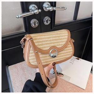 Detailed view of woven straw crossbody bag with brown leather trim and silver metal twist lock