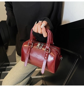 Vue détaillée du sac Boston en cuir bordeaux avec fermetures éclair argentées