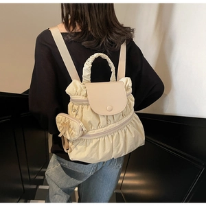 Detail view of cream pleated nylon backpack showing unique texture and mini coin purse