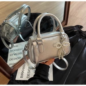 Close-up of silver oil wax leather Boston bag with pearl bow and heart charm details