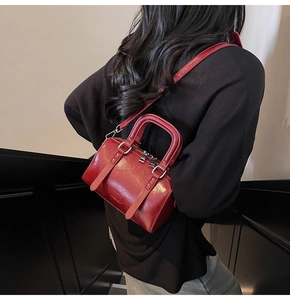 Détail d'un sac Boston en cuir rouge vif avec doubles poignées et fine bandoulière réglable