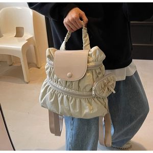 Detail of off-white pleated nylon backpack featuring a smooth faux leather flap and bow charm