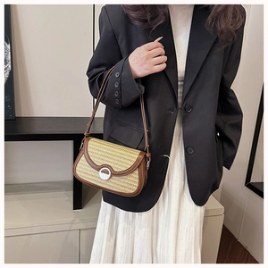 Detailed close-up of woven shoulder bag with brown leather trim and metal clasp on a model