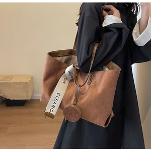 Close-up of brown suede tote bag featuring diamond stitching and embroidered wide strap