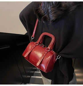 Détail d'un sac Boston rouge présentant une texture brillante et des ferrures argentées