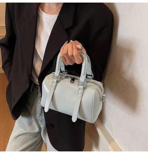Détail d'un sac Boston bleu clair en similicuir avec texte embossé et finitions soignées