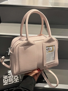 Pink faux leather Boston handbag with detachable shoulder strap on a grey step