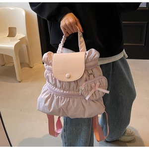 Detailed view of pink pleated nylon backpack featuring a drawstring handle and bow charm