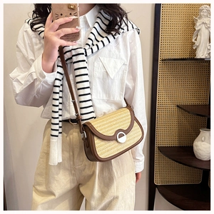 Mirror shot of a woven crossbody bag with brown leather trim and silver metal lock detail