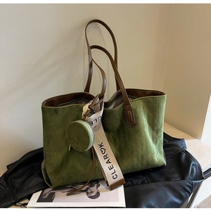Detail of dark green suede tote bag with quilted pattern and round coin purse attachment