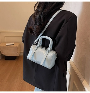 Détail du sac Boston vert menthe brillant porté en bandoulière par un mannequin