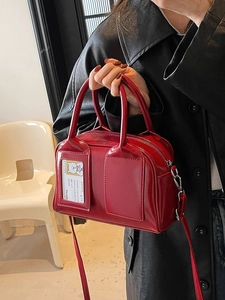 Glossy red patent leather Boston bag with top handles and a detachable shoulder strap