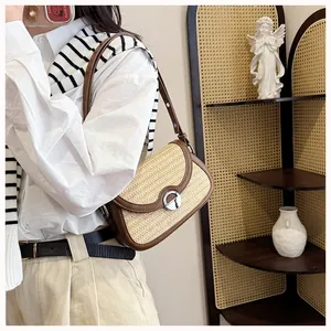 Close-up of woven straw handbag with brown leather trim and golden metal turn-lock closure