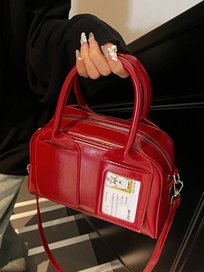 Glossy red patent leather bowling handbag with unique card slot on dark stairs