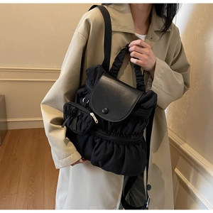 Detail view of black pleated nylon backpack with cloud-like folds and matching mini pouch