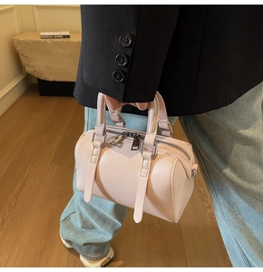 Détail du mini sac Boston rose pâle avec double poignée et texture en cuir lisse