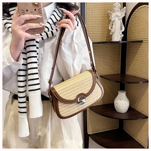 Detail of woven straw and brown leather crossbody bag with silver buckle on a model