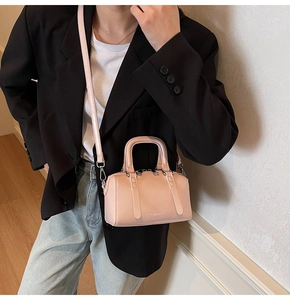 Détail d'un mini sac Boston rose clair porté avec un blazer noir pour un look élégant