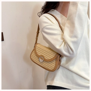 Chic woven shoulder bag with brown leather trim styled on a white V-neck sweater