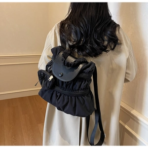 Detail view of black pleated nylon backpack with leather flap and small round pouch