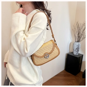 Detail of woven crossbody bag with brown leather trim and silver metal lock on a model
