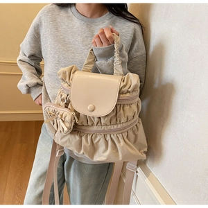 Close-up of pleated beige fabric backpack with matching mini coin purse and bow detail