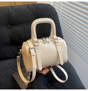 Détail d'un sac Boston blanc crème avec texture en cuir lisse sur un canapé velours